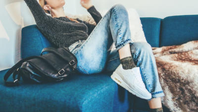 Woman sitting on couch with purse and blanket by her sides